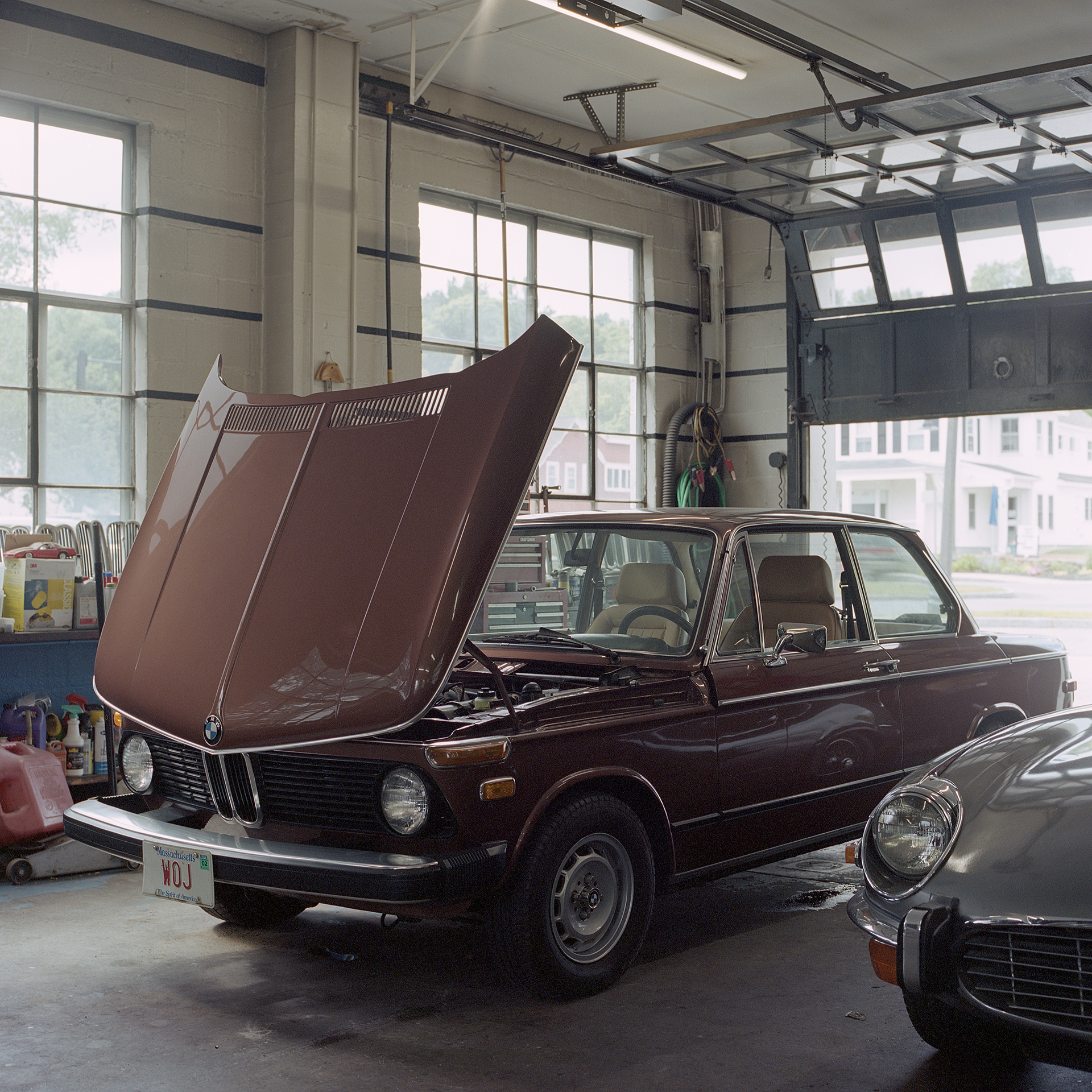 Color photo of a BMW 2002 with it's hood up in Ava Restoration Services