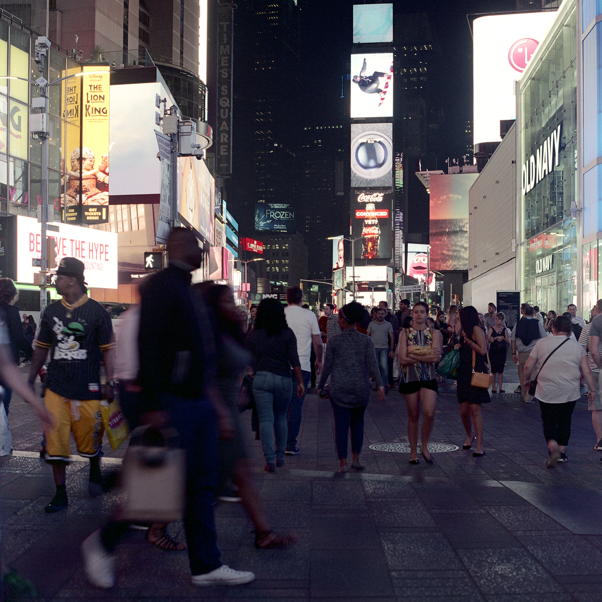 Crowds of people roam to and from places in Times Square at night