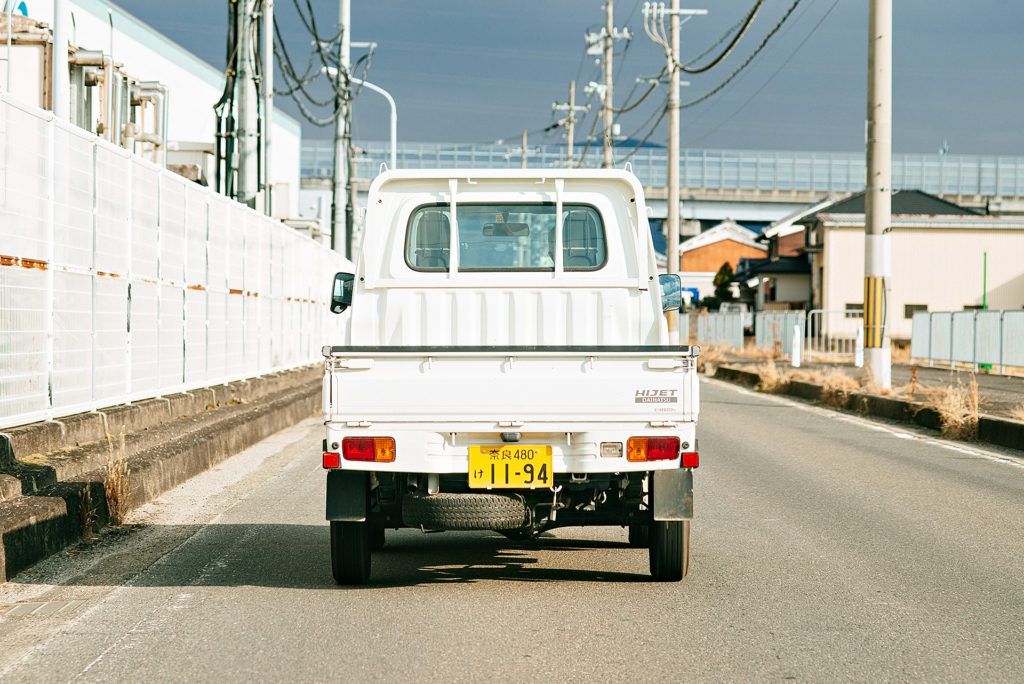 White Diahatsu Hijet driving down a street in Nara Japan